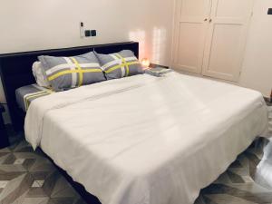 1 dormitorio con 1 cama blanca grande con almohadas y lámpara en Appartements meublés - Cozy House Bénin en Cotonú