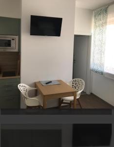 ein Wohnzimmer mit einem Tisch, Stühlen und einem TV in der Unterkunft Schindler in Münchendorf