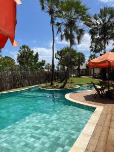 a swimming pool with palm trees in a resort at Pousada Vila Tapera in Barra Grande