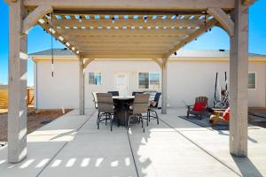 a patio with a wooden pergola with a table and chairs at Red Rock Retreat in Big Water