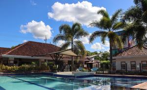 a swimming pool in front of a building with palm trees at Hotel Boutique Duranta in Villavicencio