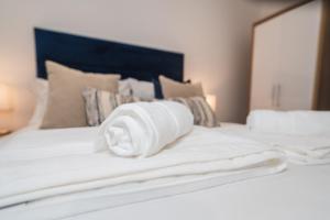 a roll of white towels sitting on top of a bed at VICHY - The Thornhill Delux Apartments in Wakefield