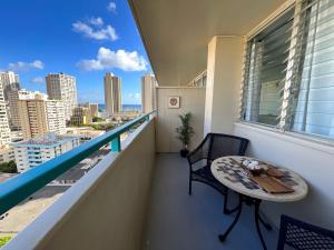 Penthouse in Waikiki with ocean & mountain views في هونولولو: شرفة مع طاولة وكراسي وإطلالة على المدينة