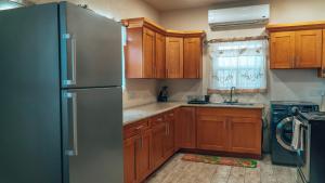 cocina con armarios de madera y nevera de acero inoxidable en SKYLINE SUITES: 3 BED/3 BATH VACATION RENTAL en Grand Anse