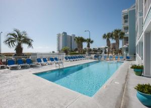 a swimming pool with blue chairs and a building at Grand Caribbean 420 by ALBVR - Great condo and views that won't break the bank. Must see! in Orange Beach