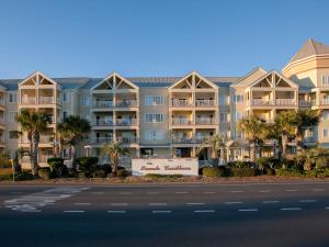 a large apartment building with palm trees in front of a street at Grand Caribbean 420 by ALBVR - Great condo and views that won't break the bank. Must see! in Orange Beach