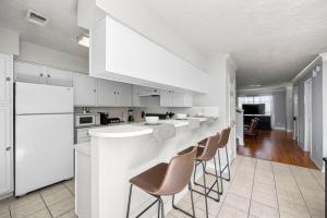 a kitchen with white cabinets and a bar with chairs at Montrose 2-Unit Retreat 4BR Sleeps 20 Near DT in Houston