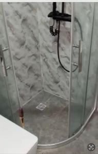 a shower with a glass door next to a toilet at Cozy Comforts in Lagos