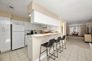 a kitchen with white cabinets and bar stools at Montrose 2-Unit Retreat 4BR Sleeps 20 Near DT in Houston