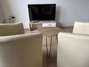 a living room with a table and a television at Central Service Apartment in Recklinghausen