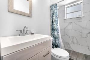 a white bathroom with a sink and a toilet at Blue Wave Bungalow - 1 1 - Stylish in Dania Beach