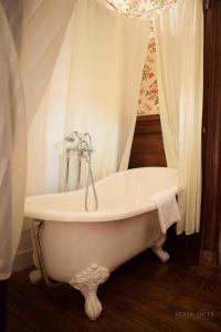 a white bath tub in a bathroom with a curtain at Château Hôtel Du Colombier in Saint Malo