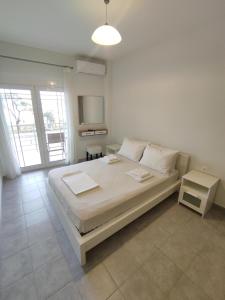 a bedroom with a large bed with white sheets and pillows at Sea View Apartments Nikos in Nea Peramos