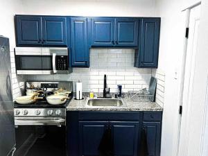 a kitchen with blue cabinets and a sink at Bright, Stunning Downtown Apt, Close to Proctors in Schenectady