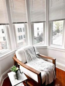 a chair sitting in a room with windows at Bright, Stunning Downtown Apt, Close to Proctors in Schenectady