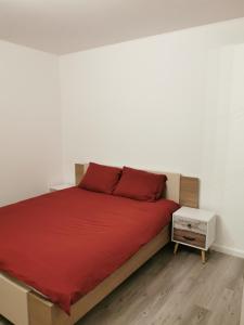 1 dormitorio con cama roja y pared blanca en AtHome - Appart-hotel with private parking en Esch-sur-Alzette