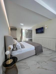 a white bedroom with a bed and a tv at ANAMA camere & suite in Lucera