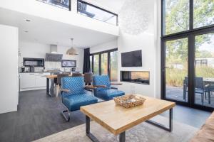 een woonkamer met een tafel en blauwe stoelen bij Holiday Home Maridu Forest Cube in Arnhem