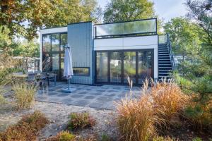 een glazen huis met een patio en een parasol bij Holiday Home Maridu Forest Cube in Arnhem