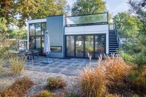 ein Glashaus mit einer Terrasse und einem Sonnenschirm in der Unterkunft Holiday Home Maridu Forest Cube in Arnhem