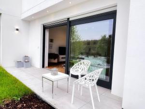 two white chairs and a table on a patio at 4-Sterne Ferienwohnung Waldblick Schweinfurt in Schweinfurt