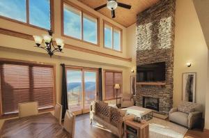 Sunset Summit Modern Mountain Retreat with Stunning Views, close to skiing and hiking في Swiss: غرفة معيشة مع موقد وتلفزيون