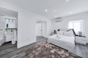 een witte slaapkamer met een bed en een badkamer bij Homey Studio near the Airport and Water Park in Miami
