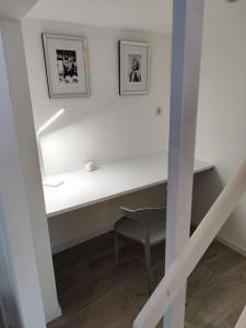 a white desk with a chair and two pictures on the wall at Grand volume calme centre-ville Tan1 in Cambrai