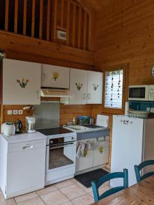 cocina con electrodomésticos blancos y techo de madera en LES CHALETS DE LA VIGNE GRANDE, en Saint-Floret