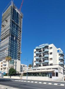 Dos edificios altos están en construcción en una calle de la ciudad. en Pigeon Beach Hotel Apartments en Limassol