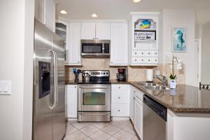 een keuken met witte kasten en een roestvrijstalen koelkast bij Aqua Breeze in Oceanside