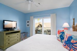 a blue bedroom with a bed and a tv on a dresser at Harbour House at the Inn 204 in Fort Myers Beach