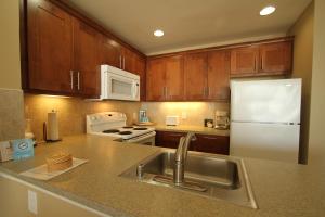 a kitchen with a sink and a white refrigerator at Sea Village in Kailua-Kona