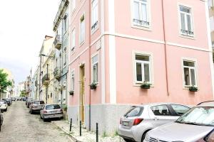 リスボンにあるSapadores · 2 bedrooms apartment Lisbon Boho Chicのピンクの建物の脇に車を停めた通り