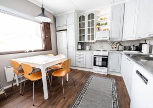 - une cuisine avec des placards blancs, une table et des chaises dans l'établissement Koivutie Apartment, à Ranua