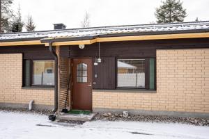a brick house with a brown door in the snow at Cozy Ranua Koivutie townhouse with sauna & terrace in Ranua