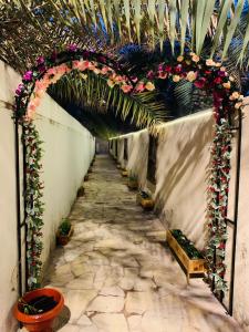 a hallway with an arch with flowers and plants at Riad Nizwa in Nizwa