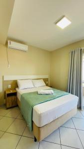 a bedroom with a bed with a green blanket and a window at Residencial 364 - Localização privilegiada à 5min da praia in Bombinhas