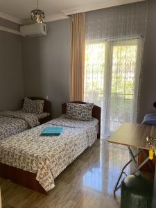 a bedroom with two beds and a table and a window at Hotel Toma in Khulo