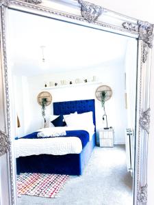 - une chambre avec un lit bleu et un miroir dans l'établissement Birmingham Fully Furnished Modern Home with Free Parking, Private Garden, Sleep 9 - 5 minutes drive to City Centre Pets allowed, à Birmingham