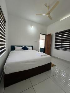 a bedroom with a large white bed with a ceiling at Hayat Residency - The Quarry Lake in Kalpetta