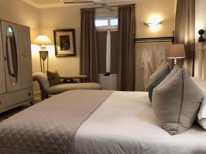 a bedroom with a large white bed and a chair at Gooding's Olive Villa in Franschhoek