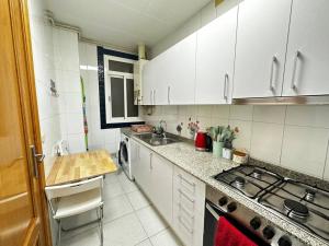 a kitchen with white cabinets and a sink and a stove at Habitaciones acogedoras in Barcelona