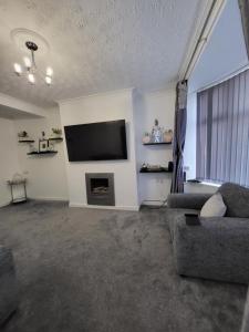 sala de estar con TV de pantalla plana y sofá en Serene 3BR home with free parking en Mánchester