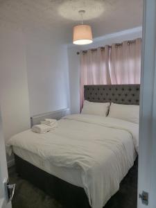 a bedroom with a large white bed with a pink curtain at Serene 3BR home with free parking in Manchester