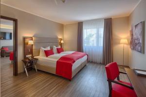 上阿斯巴赫西纽伦堡波蒙提酒店的配有红色枕头的床的酒店客房