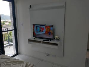 un soggiorno con una TV a parete di Flat São Vicente 5 minutos da praia a São Vicente
