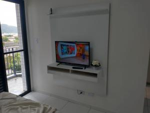 a living room with a tv on a wall at Flat São Vicente 5 minutos da praia in São Vicente