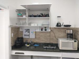 a kitchen with a sink and a microwave at Flat São Vicente 5 minutos da praia in São Vicente