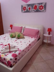 een bed met roze en witte lakens en kussens bij Rainbow Apartment in Scordia